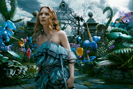 Mia Wasikowska com vestido largo, em cenário colorido de floresta